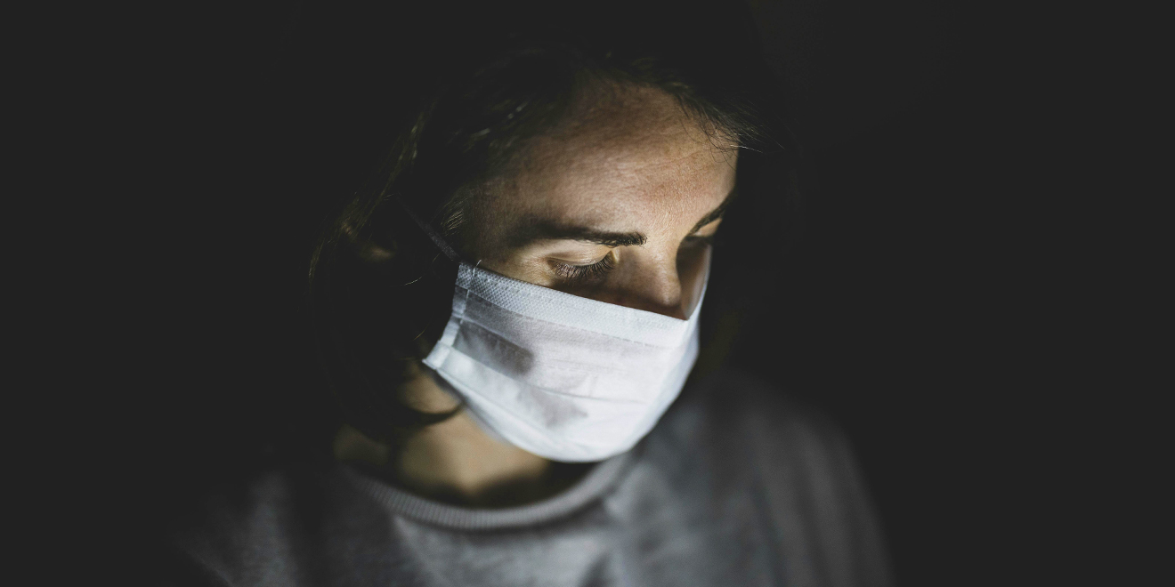 Healthcare Worker with PP2 face protection on illuminated by a digital screen out of shot in a dark environment