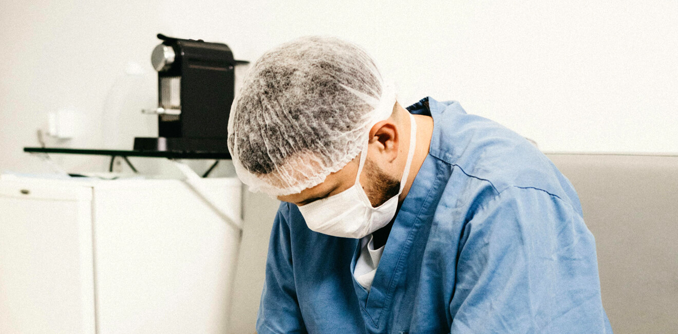 Exhausted male nurse sitting staring dejectedly at the floor on a hospital seat in a medical environment