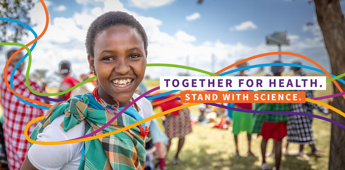 A young African girl smiling at the camera surrounded by her elders with the words 'Together for Health' and 'Stand with Science' overlaid to her right on the image