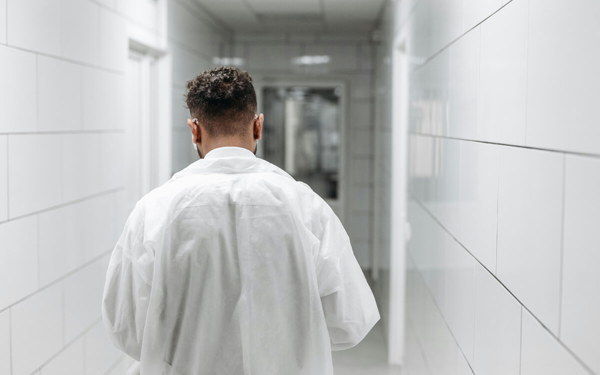 A healthcare professional walking through medical facility corridors with a protective mask on